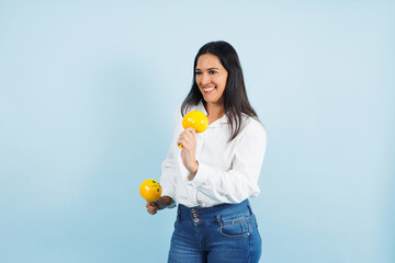 portrait of adult mexican woman dancing and holding maracas on blue background in Mexico Latin America, or Latina middle aged brunette female 