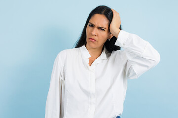 portrait of adult mexican woman with headache pain on blue background in Mexico Latin America, or Latina middle aged brunette female feeling bad