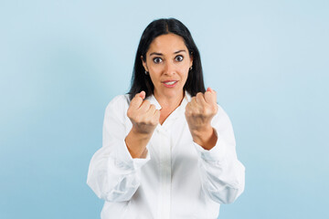 portrait of adult mexican woman in fighting stance on blue background in Mexico Latin America, or Latina middle aged brunette female