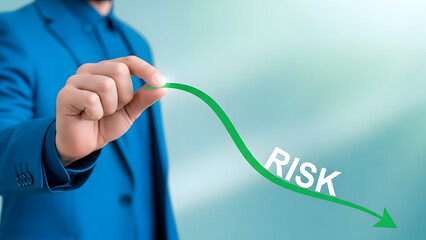 Businessman's hand guiding a downward green arrow labeled 'RISK,' symbolizing effective strategies for risk reduction and successful business management