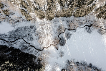 Winter rural landscape from a drone. Snow, stream, and forest.