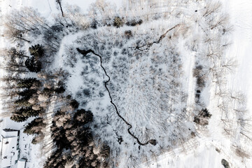 Winter rural landscape from a drone. Snow, stream, and forest.