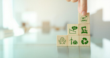 Wooden blocks with green eco friendly symbols on a reflective surface in a bright room