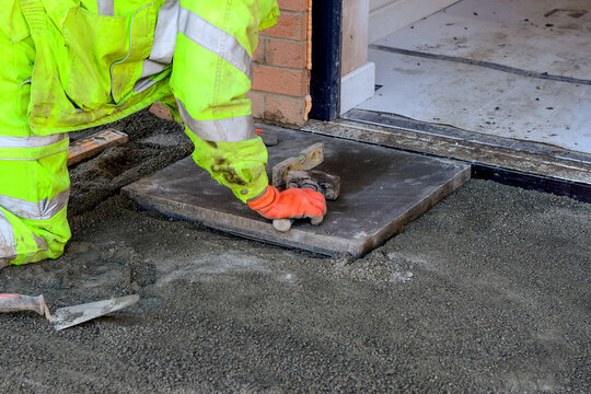 Paving works in progress as builder laying concrete paving slabs for new footpath or patio