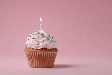 Single birthday cupcake with lit candle and sprinkles on a pink background