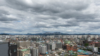 Naklejka premium Dense residential apartment district under a dramatic cloudy sky with mountain view