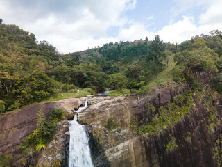 Obraz premium Aerial view of Diyaluma Falls in Sri Lanka. Powerful waterfall cascading through lush green landscape, dramatic natural scenery, tropical nature and adventure travel destination seen from above.