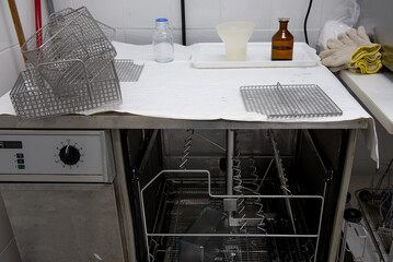 Laboratory dishwasher with baskets and laboratory bottles on top.