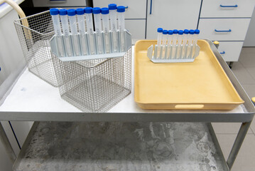 Laboratory transport trolley made of metal, with two shelves. White protective paper on the top shelf, various laboratory items on it,.