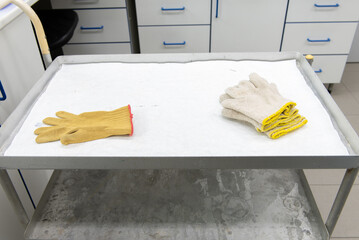 Laboratory transport trolley made of metal, with two shelves. White protective paper on the top shelf, various laboratory items on it.