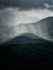 Rain falls on the dark green mountains of Ireland, creating an atmospheric, misty scene.