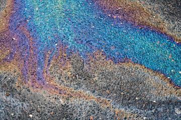 Gasoline spill creating colorful abstract pattern on wet asphalt surface