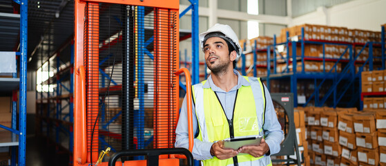 Professional warehouse workers using digital tablet with forklift and pallets. Logistics team management, inventory control, and industrial supply chain concept.