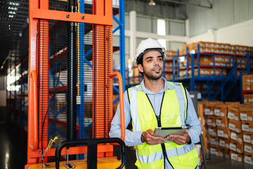 Professional warehouse workers using digital tablet with forklift and pallets. Logistics team management, inventory control, and industrial supply chain concept.