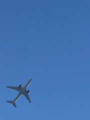 Fototapeta premium Airplane flying across a clear blue sky with copy space.