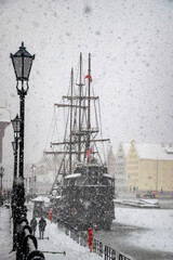 Beautiful ancient sail ship moored on the embankment of frozen Motlawa river in Gdansk