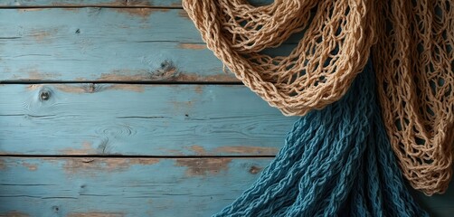Rustic blue wood and fishing nets on tabletop. Beige mesh and turquoise ropes create marine decor. Wood texture has space. Nautical theme background for sea adventures and summer vacation.