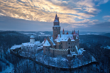 Bouzov Castle winter aerial at blue hour, medieval fortress above snowy forest, Czech Republic