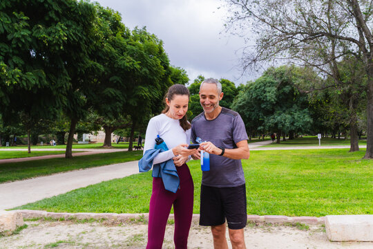 Two friends forty years old or more looking at a smartphone screen in a park
