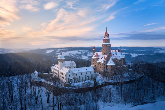 Bouzov Castle winter aerial at sunset, medieval fortress above snowy forest, Czech Republic
