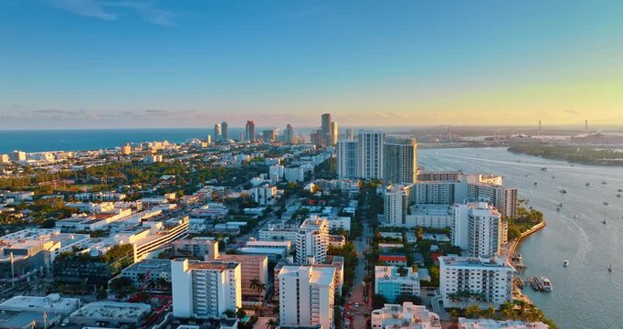 Footage over the beautiful cityscape of Miami at sunset time. Blue waterscape surrounds the urban landscape. Aerial view.