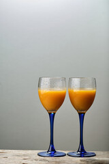 Two Glasses of Peach Juice on a Wooden Table Against a Gray Background