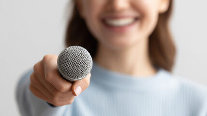 Smiling woman holding a microphone toward the viewer representing interviews communication and public speaking concept
