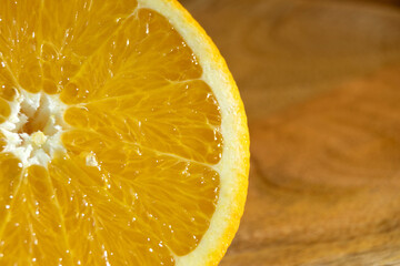 An orange cut in half on a wooden tray illuminated by a beam of light