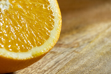 An orange cut in half on a wooden tray illuminated by a beam of light