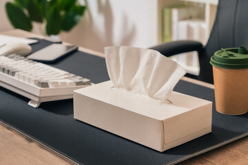 A box of tissues sits on a desk next to a keyboard and a cup. Concept of comfort and familiarity, as tissues are often associated with caring for oneself or others during times of illness or stress