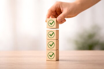 Hand stacking wooden blocks with green checkmarks on a table