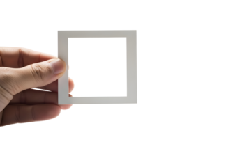 Hand holding a small white square frame cutout against a bright transparent background