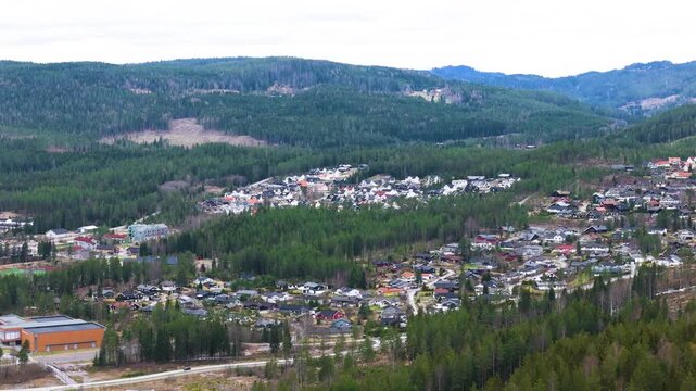 norway panorama hillside town colorful houses winding roads dense forests mountain ridges clear cut patches sit under overcast sky wide drone clear-cut 