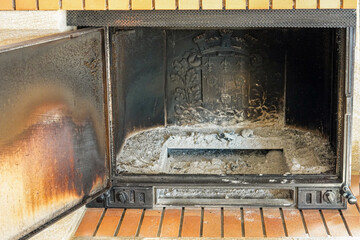 Ashes and soot fill the empty fireplace area