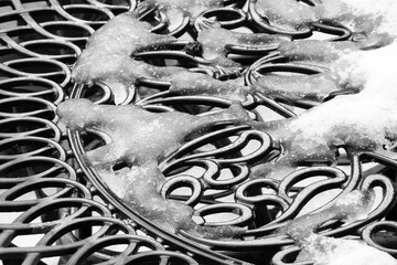 Winter snow on a wrought iron patio table closeup