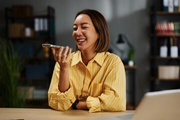 Woman joyfully recording a voice message using her phone for modern communication