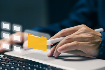 Business professional managing digital folders on laptop, representing file organization, document management system, cloud storage, data classification, and paperless workflow.