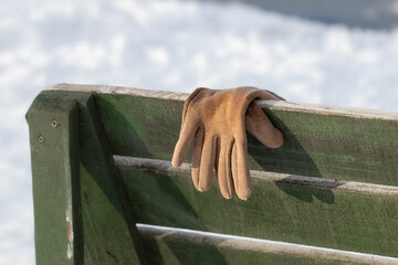 A woman's glove forgotten by someone on a bench in a winter park.Scene from life.
