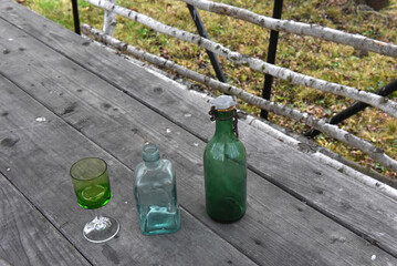 Vintage green and clear glass bottles and stemmed cordial glass for rustic decor and collecting