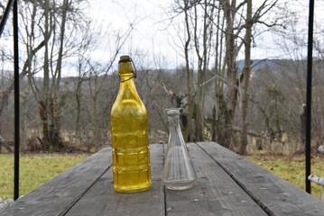 Yellow and clear vintage glass bottles on wooden table in nature setting for decor and collection
