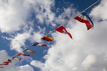 Bandeiras internacionais a esvoa&ccedil;ar ao vento sob um c&eacute;u parcialmente nublado.