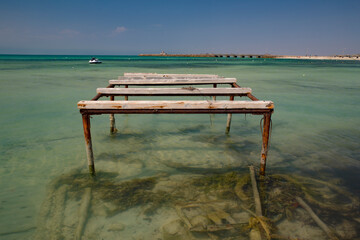 Cais abandonado sobre &aacute;guas cristalinas num dia ensolarado.