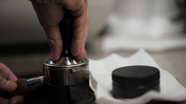 Barista tamping ground coffee in portafilter