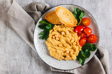 Close up of chickpea puree, tomatoes, toast and greens on a plate on the table top view