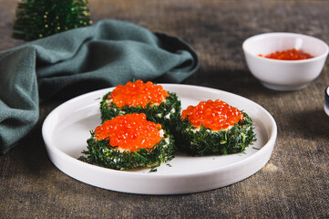 Original small sandwiches with butter and red caviar on a plate on the table