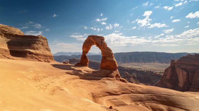 4K Delicate arch framed by sandstone formations in arches national park, utah, under a vibrant blue sky with scattered clouds, a majestic desert landscape video