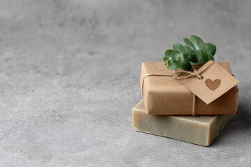 Natural soap kraft paper wrap twine tag heart label eucalyptus leaf grey stone background handmade gift eco friendly minimal style rustic aesthetic. Natural soap wrapped kraft paper with twine