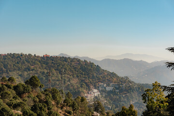 Obraz premium Mountain Serenity: A Vista of Lush Hills, Distant Peaks, and Clear Skies in a Hazy Landscape, Perfect for Travel, Nature, and Scenic Backdrop Views
