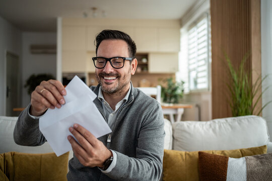 Smiling man opening mail letter with good news