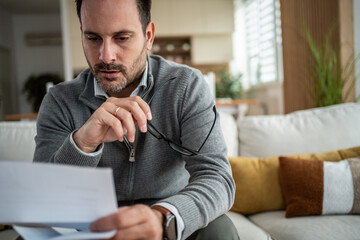 Fototapeta premium Man feeling concerned reading document at home